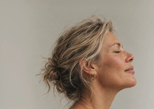 A woman in profile with her hair loosely pinned up, eyes closed